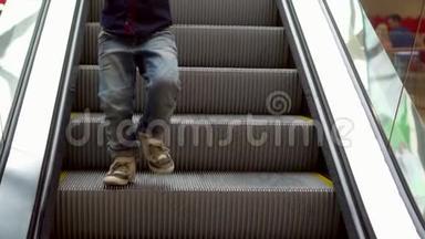 小男孩站在自动扶梯上。 这个男孩在购物中心的自动扶梯台阶上下来。 圣诞节购物。 慢慢